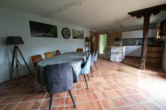 The living room: long table, carved timber post and the open kitchen beyond