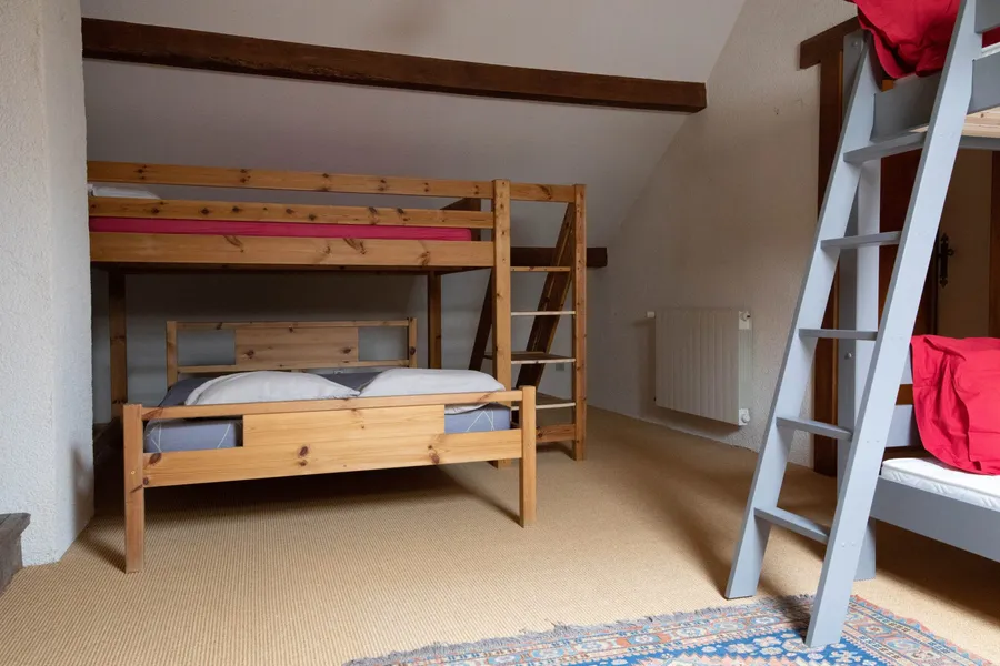 Le dortoir sous les combles : lit double, couchage en mezzanine et lits superposés sous les poutres