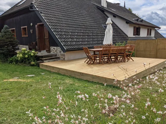 The wooden terrace and its long table, below the farmhouse roof