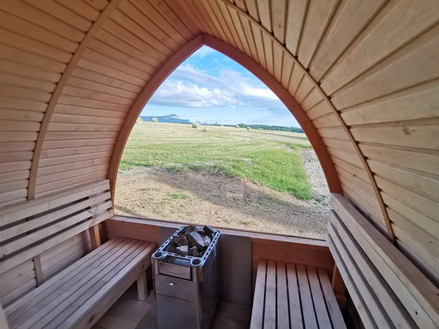 Inside the sauna in summer, the window open onto the field and the mountains