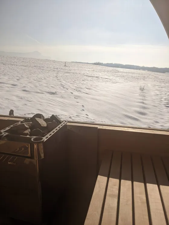 L'intérieur du sauna en hiver, le poêle et le champ enneigé derrière la vitre