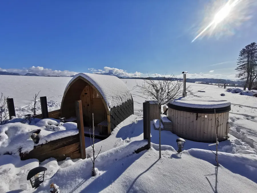 The sauna and hot tub in the snow, facing the mountains